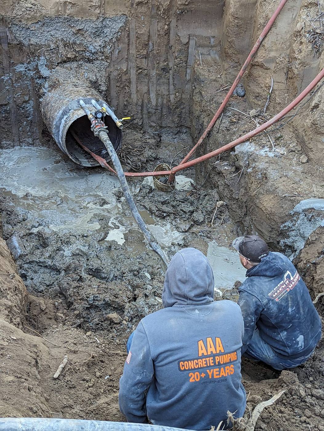 Crew pumping cellular grout into a large corrugated pipe