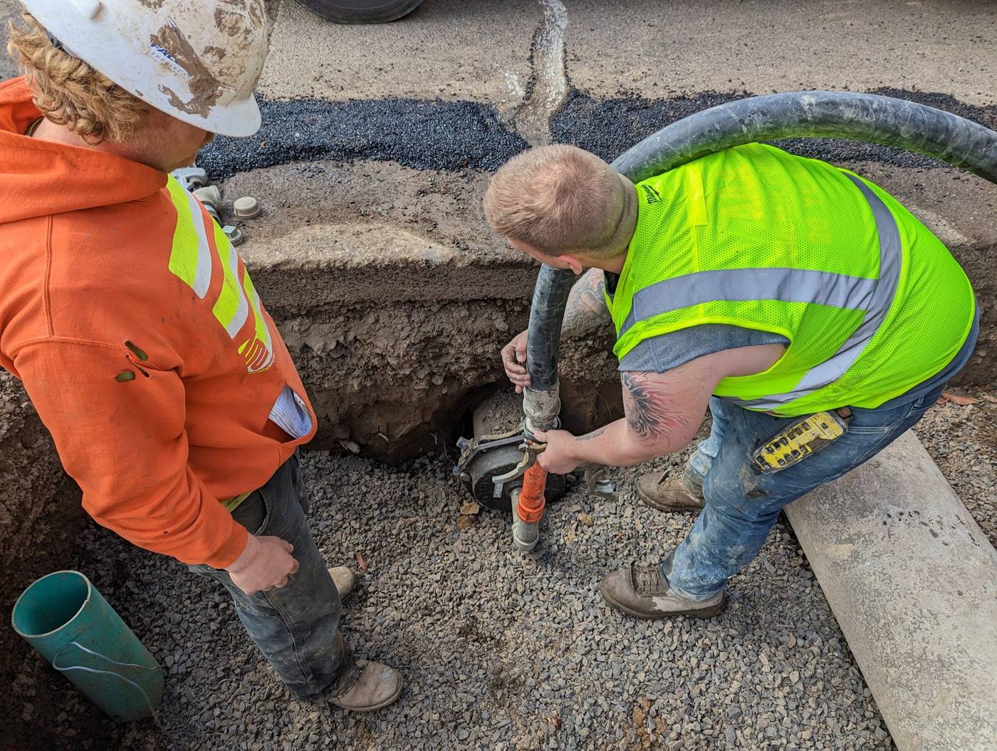 Crew connecting a grout hose to a pipe for abandonment fill